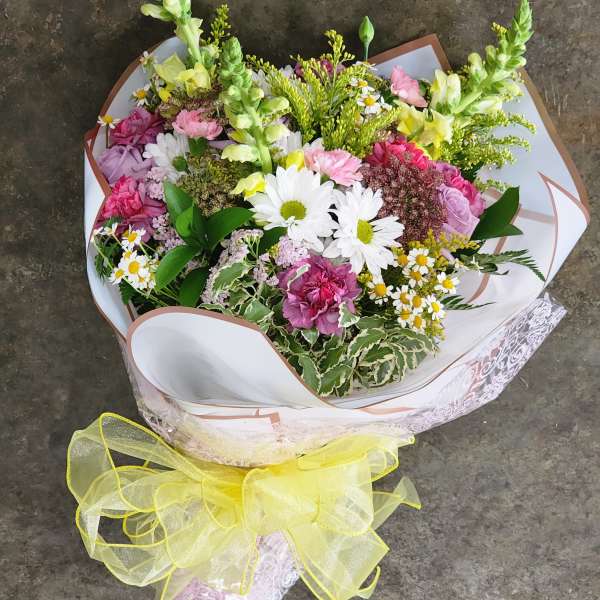 Mixed bouquet of pink, white, and yellow flowers wrapped with a yellow ribbon