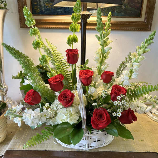 Basket arrangement of red roses and white flowers with tall green spikes