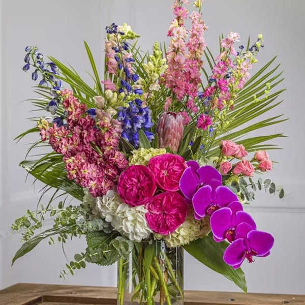 Tall mixed bouquet in a clear glass vase with pink, purple, and white flowers
