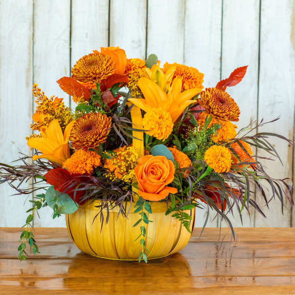 Orange and yellow floral arrangement in a pumpkin-shaped container