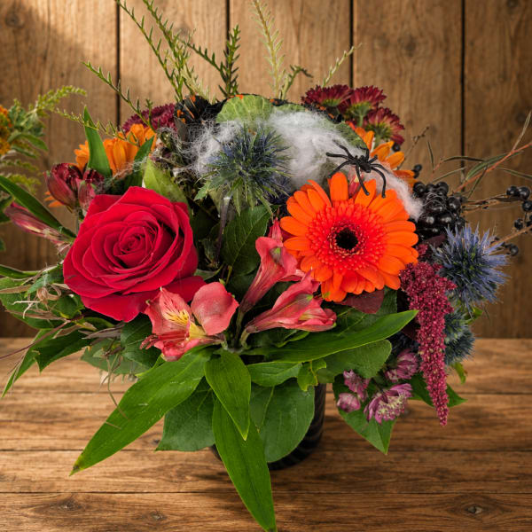 Colorful mixed flower arrangement in a black vase on a wooden table