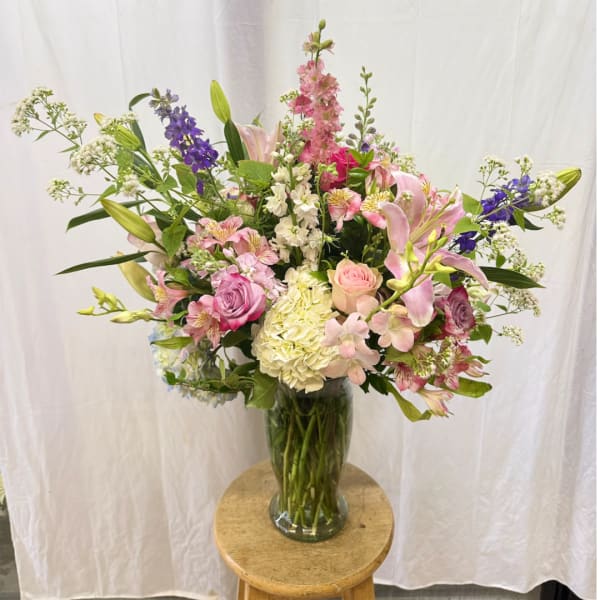 Large mixed bouquet in a clear glass vase with pink and purple flowers