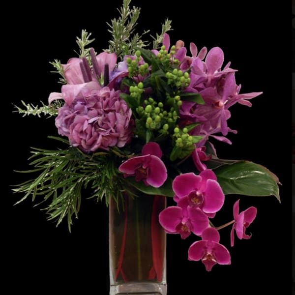 Pink and purple floral arrangement in a tall glass vase