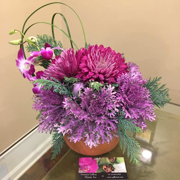 Purple floral arrangement in a terracotta bowl with arching orchid stems
