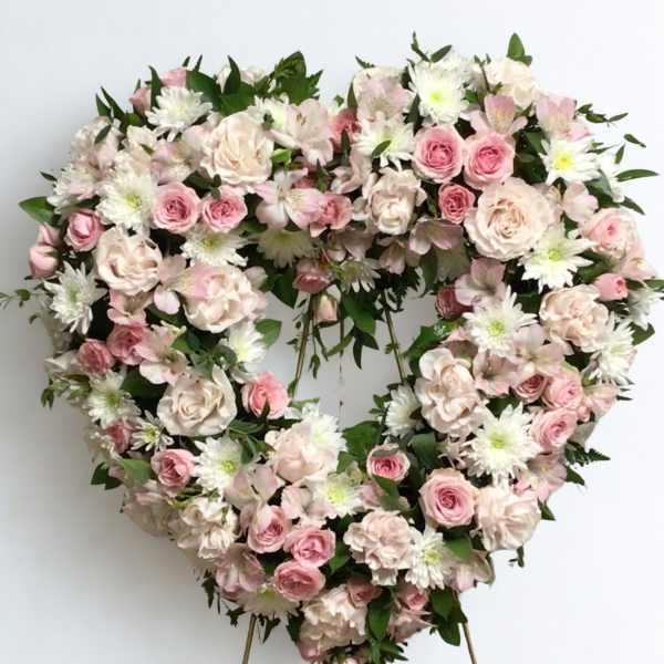 Heart-shaped floral wreath with pink and white flowers on a stand