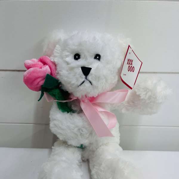 White plush teddy bear holding a pink fabric rose with a pink ribbon and gift tag