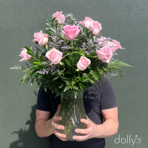 Pink roses in a glass vase held by a person