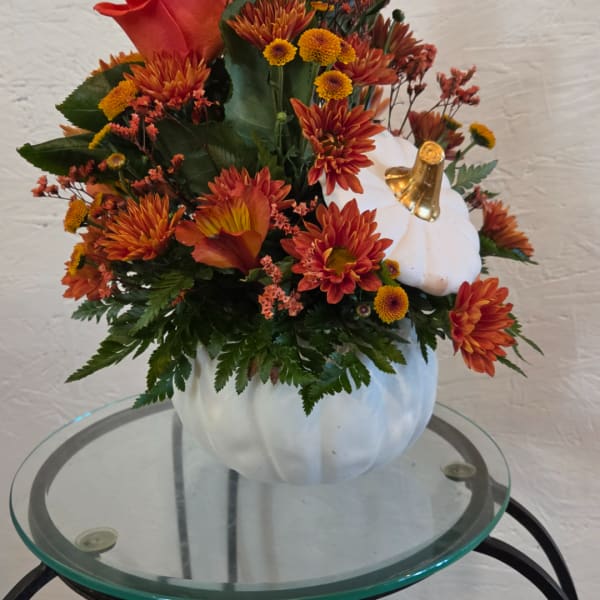 Orange chrysanthemum arrangement in a white pumpkin vase