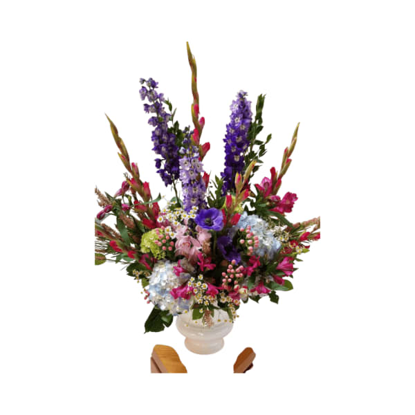 Tall mixed flower arrangement in a white vase with purple, pink, and blue blooms