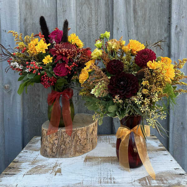 Two autumn flower arrangements in glass vases with ribbon bows