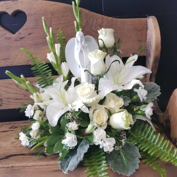 White floral arrangement with lilies and roses on a wooden bench