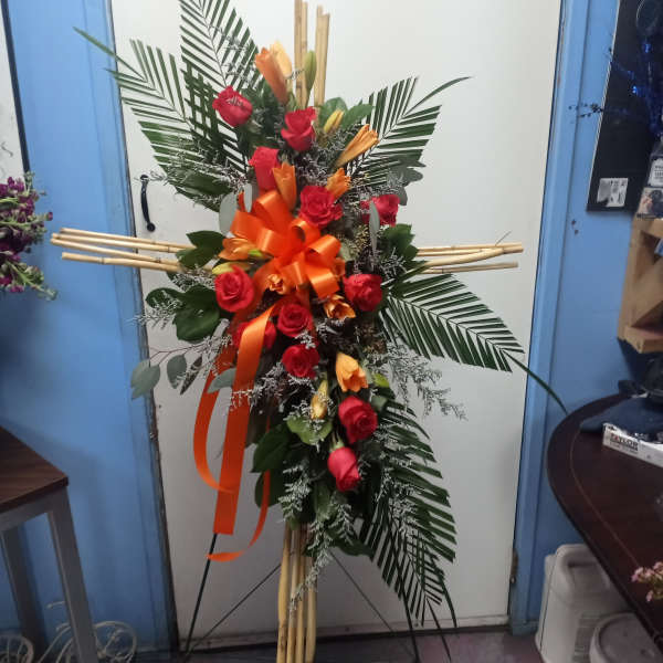 Tall standing floral spray with red roses and orange lilies on a bamboo easel