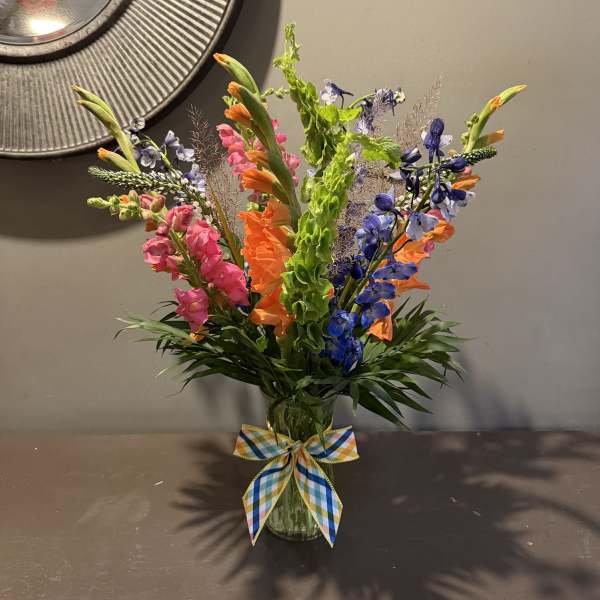 Colorful mixed bouquet in a glass vase with a plaid ribbon