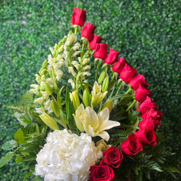 Red roses and white lilies arranged with white hydrangea in a basket