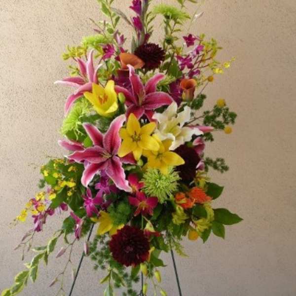 Tall mixed floral spray with pink lilies and yellow blooms on a stand