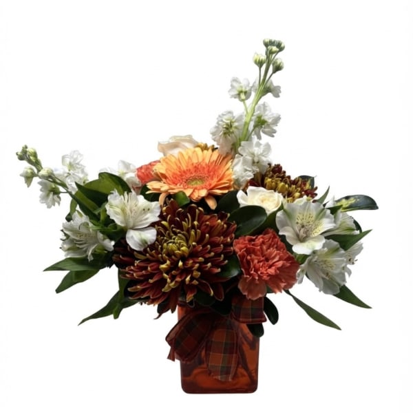 Mixed bouquet in an amber vase with orange, white, and burgundy flowers