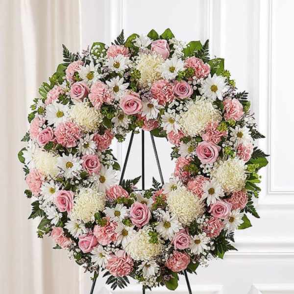 Pink and white floral wreath on a black stand