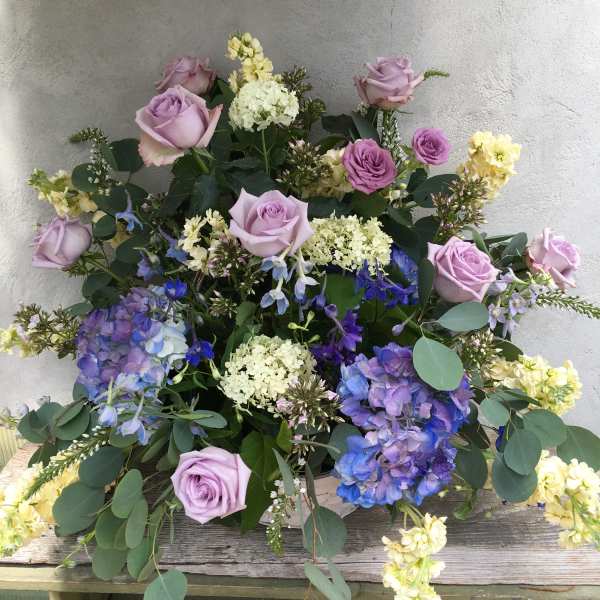 Lavender roses and blue hydrangeas in a low floral arrangement