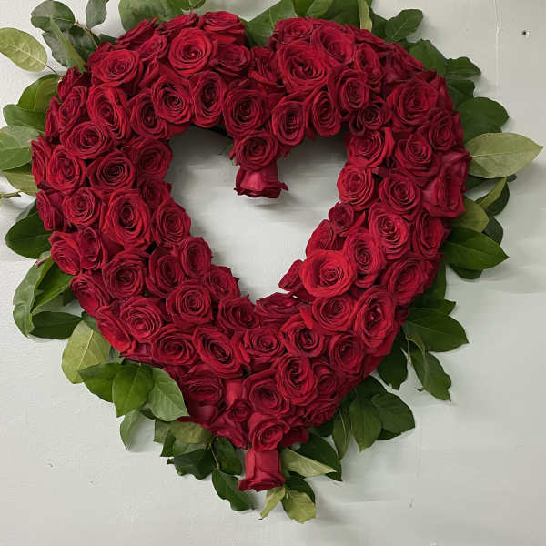 Heart-shaped arrangement of red roses with green foliage