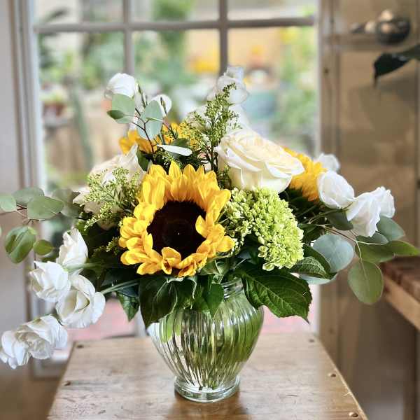 Sunflower and white rose arrangement in a clear glass vase