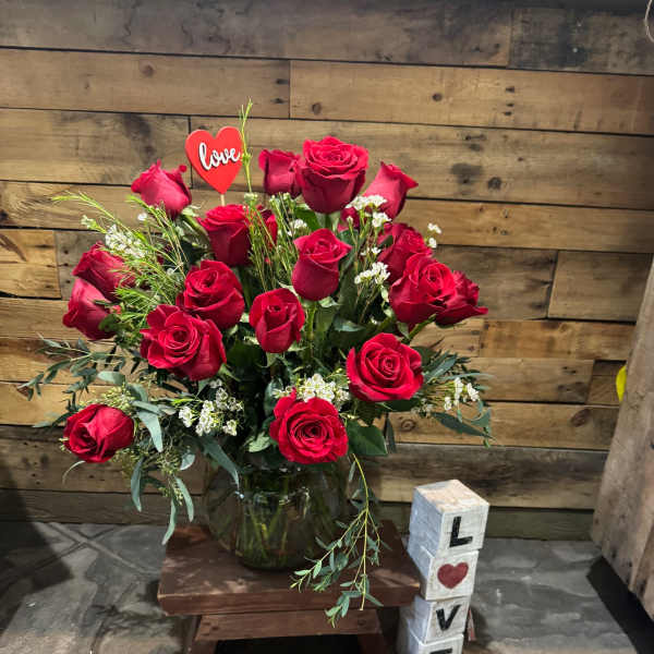 Red roses in a glass vase with love-themed decorations