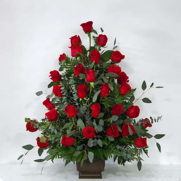 Tall arrangement of red roses in a brown vase