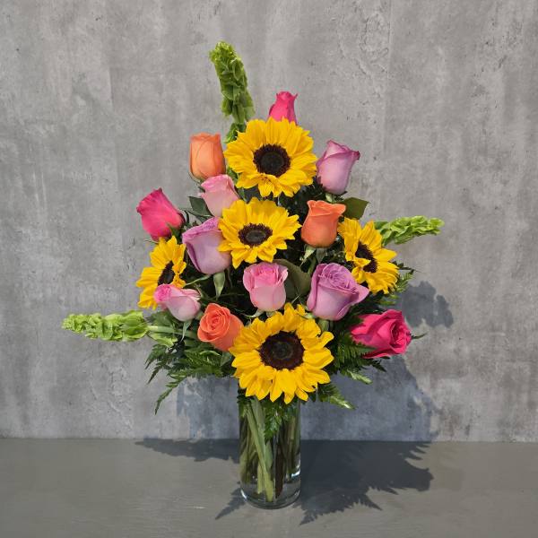 Mixed bouquet of sunflowers and roses in a clear glass vase