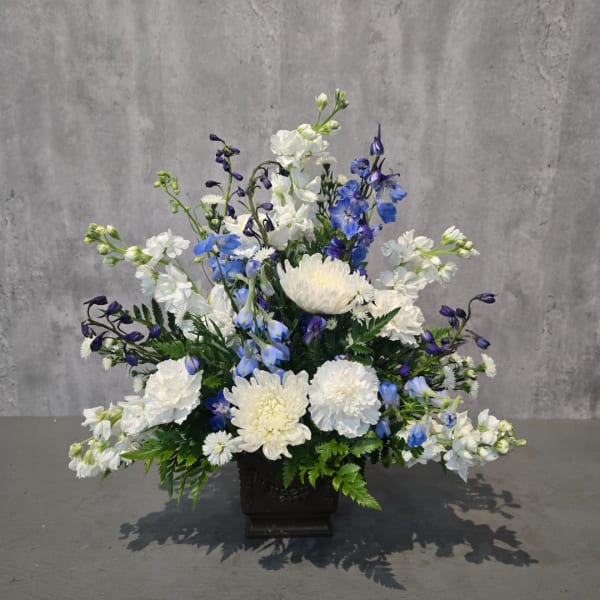 White and blue floral arrangement in a dark square vase