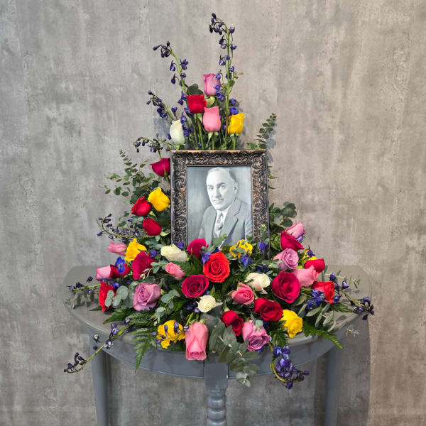 Colorful rose arrangement around a framed black-and-white portrait