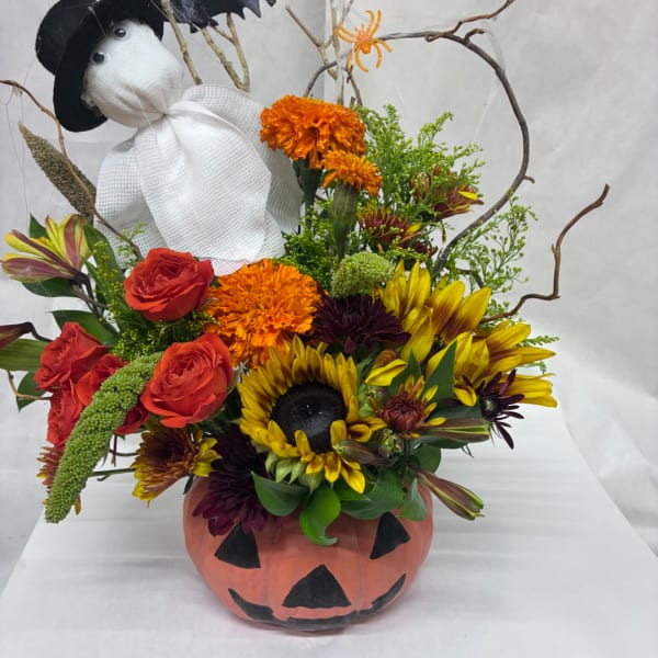 Halloween floral arrangement in a painted pumpkin container with a stuffed ghost