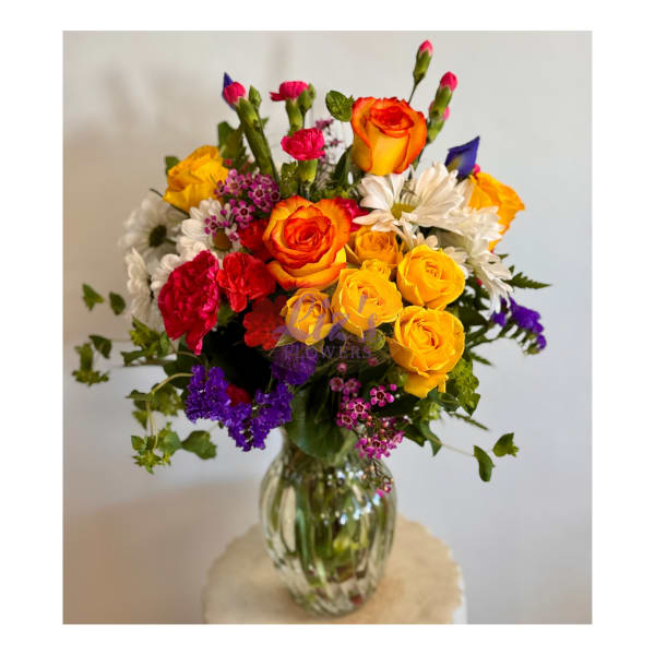 Colorful bouquet of roses, carnations, and daisies in a glass vase