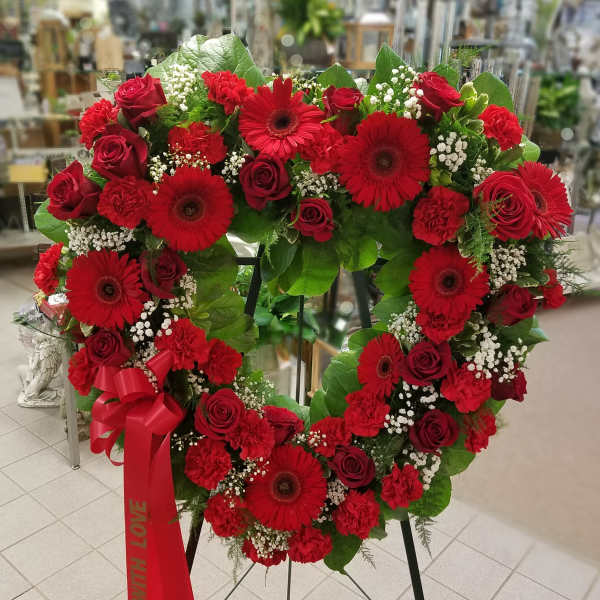 Heart-shaped red floral wreath on an easel with a red ribbon