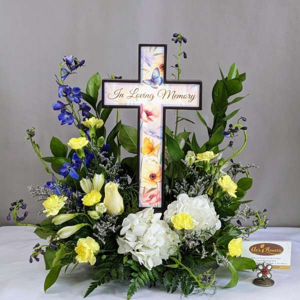 Memorial floral cross with white and yellow flowers and blue accents