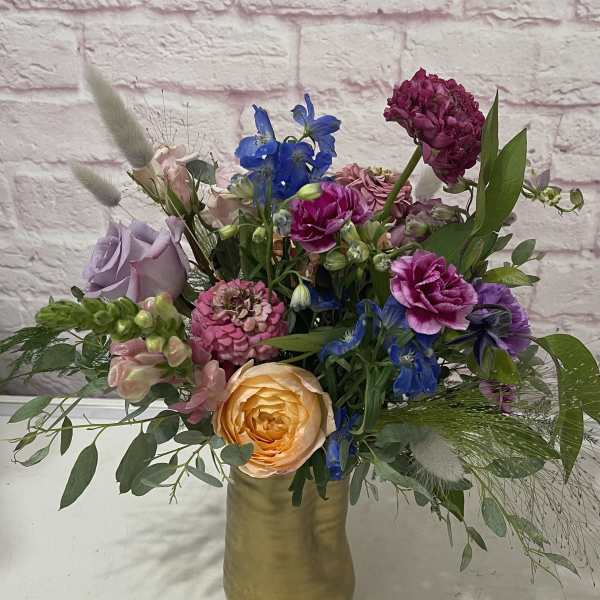 Mixed bouquet in a gold vase with roses and blue flowers