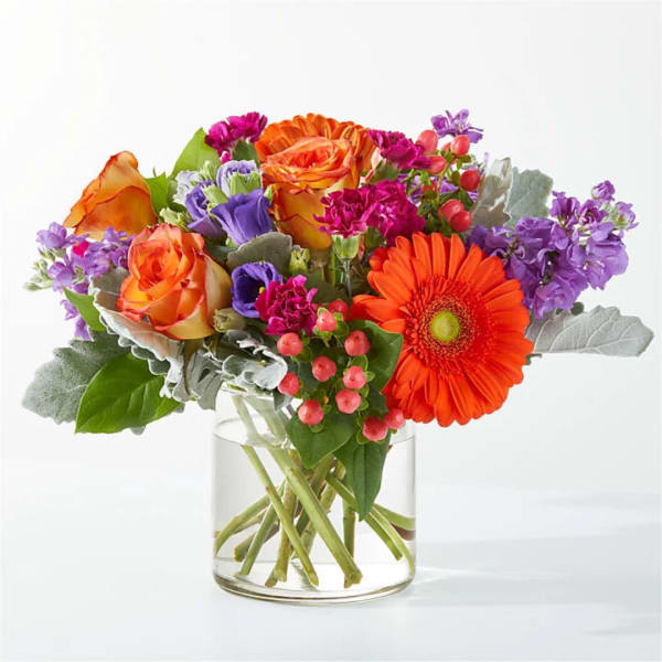 Orange and purple mixed bouquet in a clear glass vase