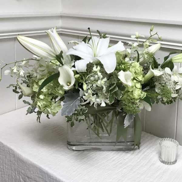 White lilies and green-white flowers in a clear glass vase