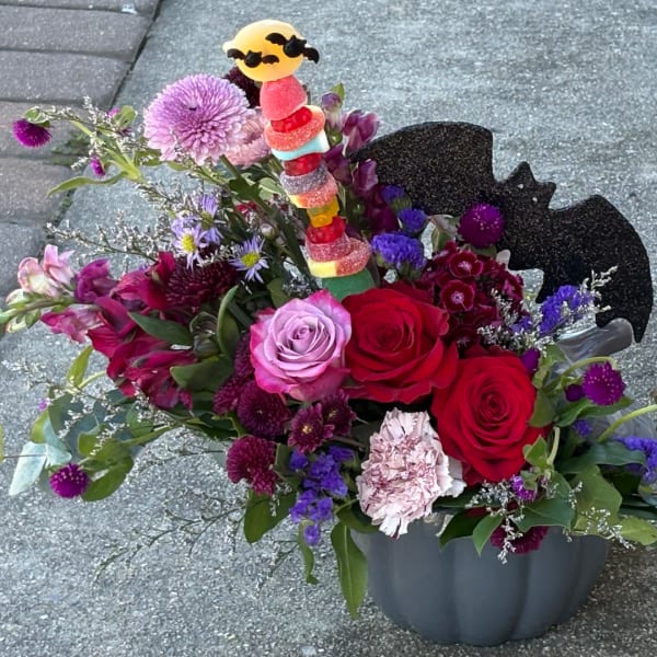 Colorful bouquet with roses, carnations, and a candy topper in a vase