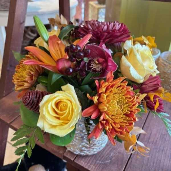 Mixed bouquet of roses, lilies, and chrysanthemums in a glass vase