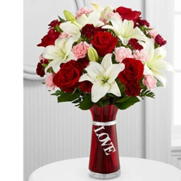 Bouquet of red roses, white lilies, and pink carnations in a red vase