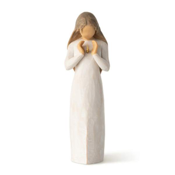 Small angel figurine in a long white dress holding a tiny gold ornament
