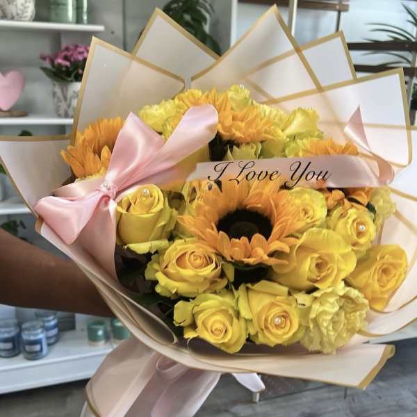Yellow roses and orange sunflowers in pink wrapping with a ribbon