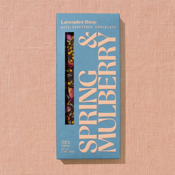 Blue box of lavender rose date-sweetened chocolate on a pink fabric background