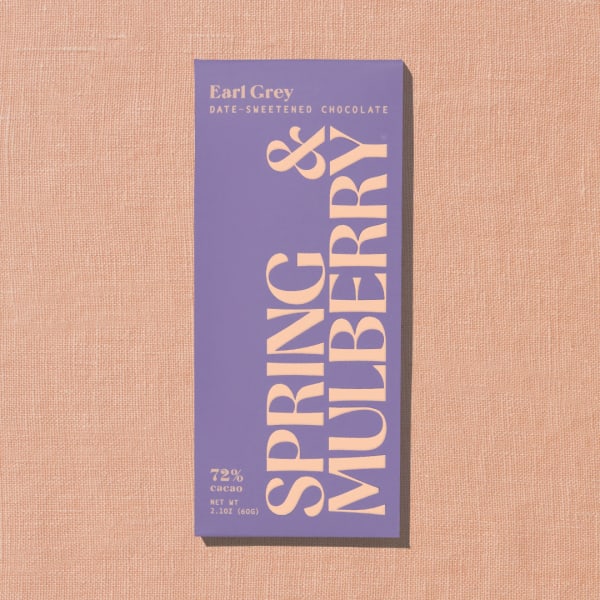 Purple Earl Grey chocolate bar package on a peach textured background