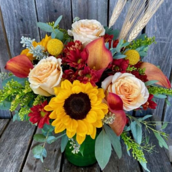 Bouquet with sunflowers, cream roses, and red calla lilies in a green vase