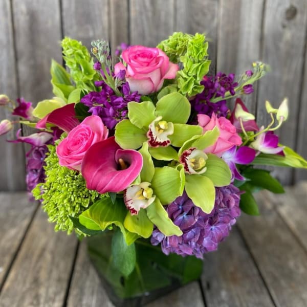 Bright pink and purple bouquet with green orchids and calla lilies in a vase