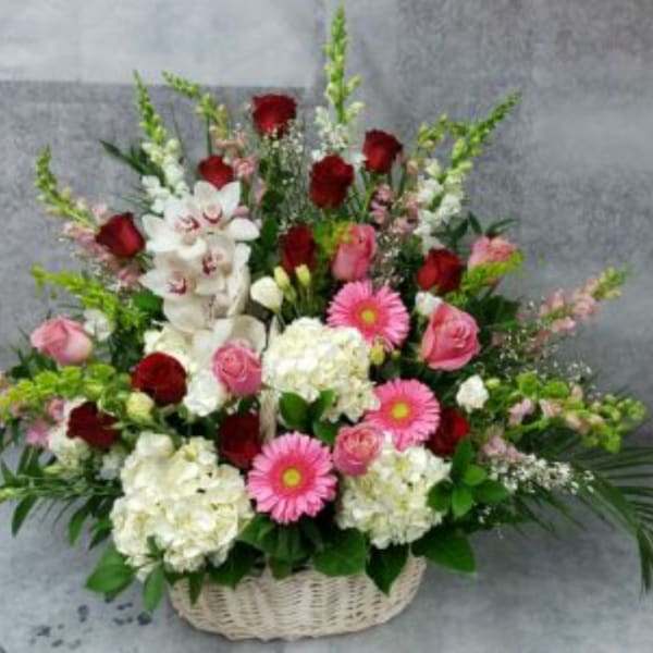 Basket arrangement of red and pink roses with white orchids and daisies