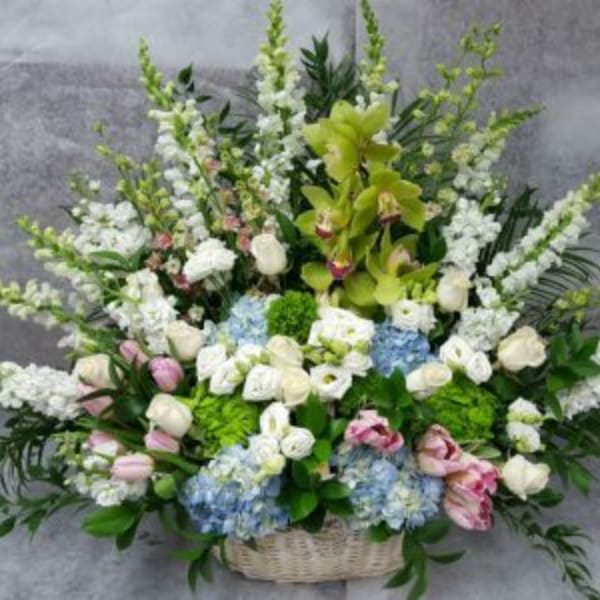 Large basket arrangement with white and pastel flowers and tall green spikes