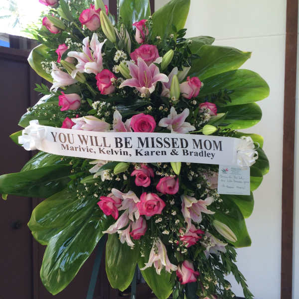 Standing sympathy spray of pink roses and lilies with a memorial ribbon
