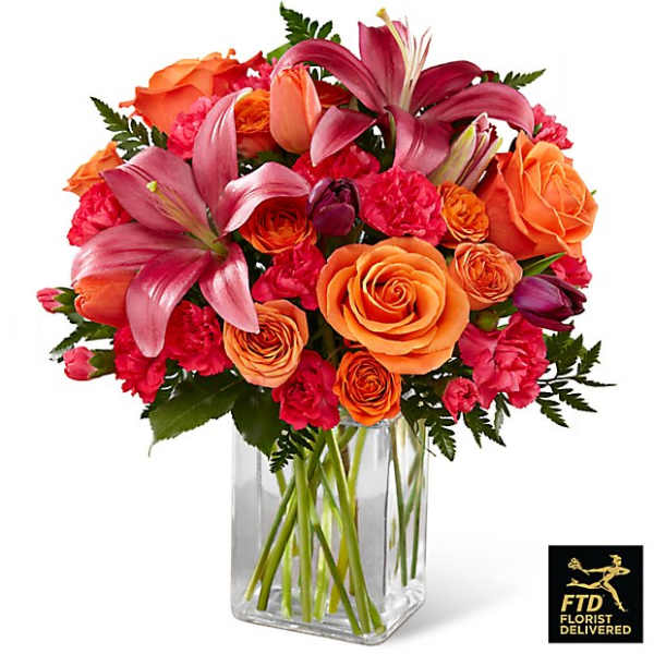 Bouquet of orange roses and pink lilies in a clear glass vase