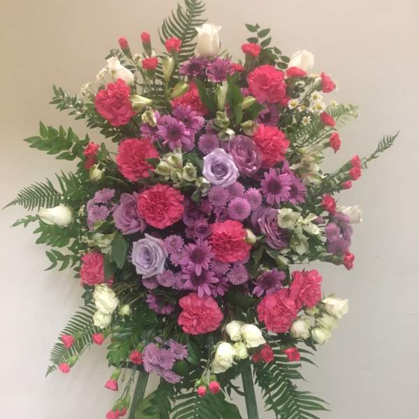Large standing floral spray with pink, purple, and white blooms